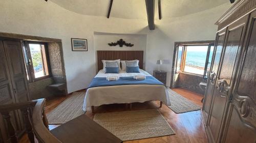 a bedroom with a bed with blue sheets and a window at In Apúlia - Moinho do Mar in Apúlia