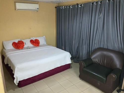 una camera da letto con due cuori su un letto e una sedia di Optizee Hotel & Suites a Omole