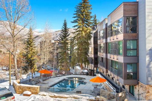 an apartment building with a swimming pool and orange umbrellas at Renovated 2 BR Aspen Condo Ski-in out in Aspen