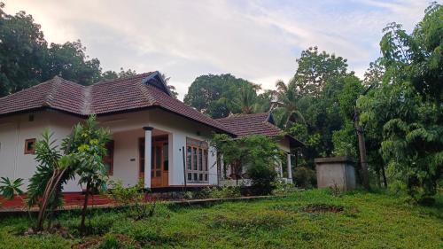 a house in a field with trees in the background at Mountain View Villa Vacation Rental in Idukki