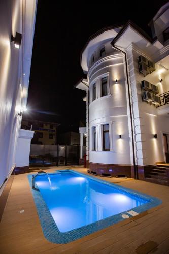 a swimming pool in front of a house at night at Hotel Ak Saray in Tashkent