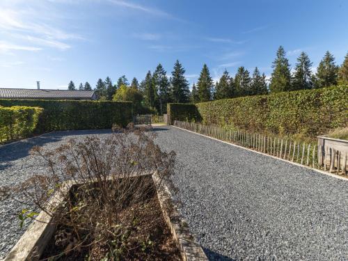 a garden with a gravel road next to a hedge at Lush chalet near lake of Bütgenbach in Wirtzfeld