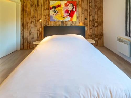 a large white bed in a room with wooden walls at Lush chalet near lake of Bütgenbach in Wirtzfeld
