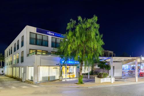 a white building with a tree in front of it at Hotel Vibra s'Estanyol in San Antonio Bay