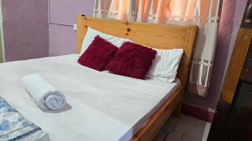 a bed with red and white pillows on it at Okla GuestHouse in Kampala
