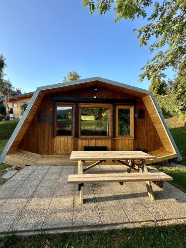 a large wooden cabin with a picnic table in front of it at ''Le Nid Alpin'' Petit cocon avec vue sur les pistes de Métabief in Métabief