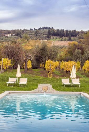 a swimming pool with chairs and umbrellas and a playground at Apartment With View In The Heart Of Chianti in Scopeti