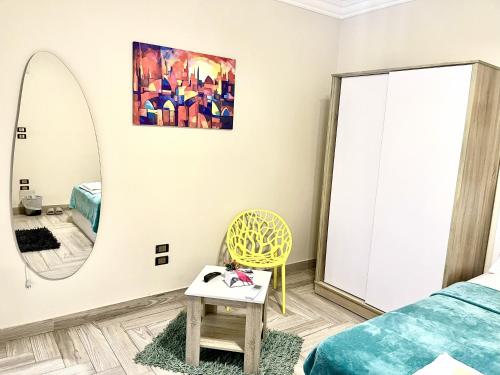 a bedroom with a mirror and a yellow chair at Rose Room in Cairo