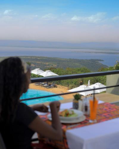 a woman sitting at a table with a plate of food at Mantis Akagera Game Lodge in Akagera
