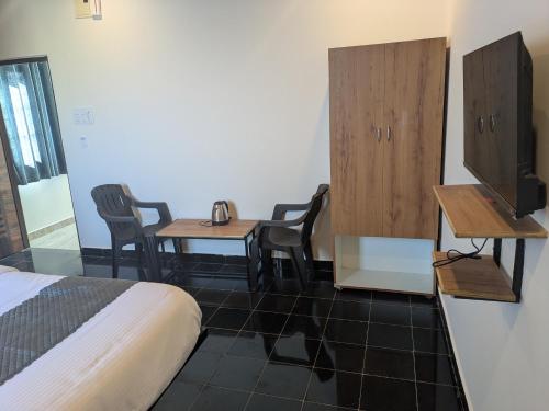 a room with a bed and two tables and a tv at Hotel Virat Stay in Hyderabad