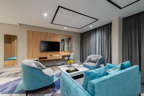 a living room with blue furniture and a flat screen tv at فندق رينيوم - جازان in Jazan