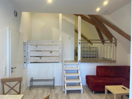a living room with a ladder and a red couch at Ferienwohnungen im Stollenhof in Schnelldorf