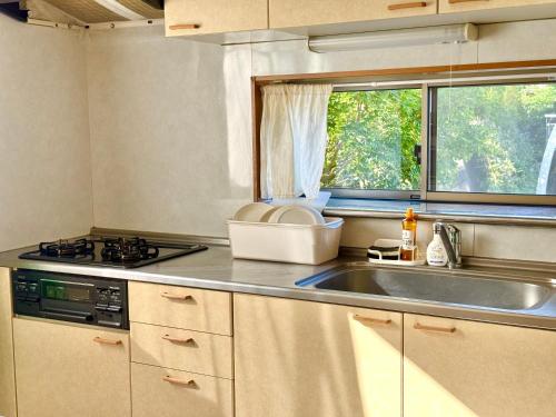 a kitchen with a sink and a stove and a window at Izu Shirada Villa 伊豆白田家 in Higashiizu