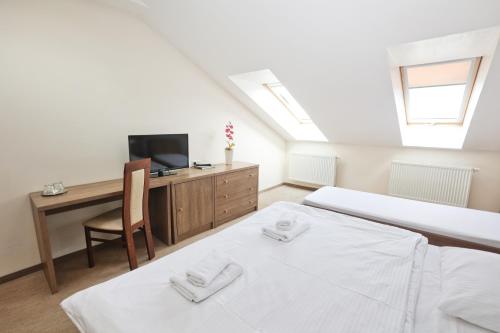 a bedroom with two beds and a desk and a tv at Penzión Zlatny Potok in Mutné