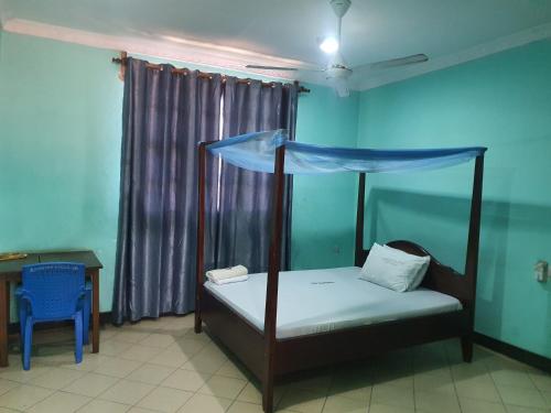 a bedroom with a canopy bed and a table at Sengiya Inn in Tanga