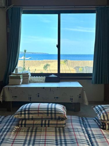 a bedroom with a view of the beach from a window at Izu Hokkawa Seaside Guesthouse 伊豆北川の家 in Higashiizu