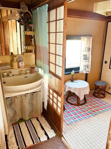 a bathroom with a tub and a table in a room at Izu Hokkawa Seaside Guesthouse 伊豆北川の家 in Higashiizu