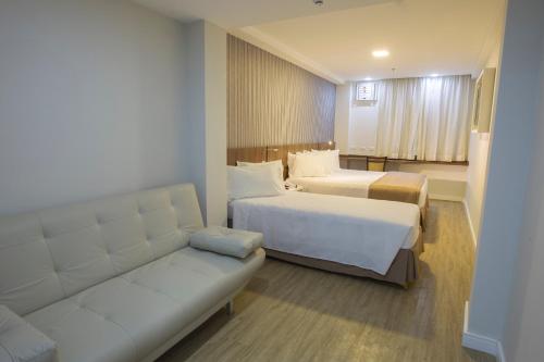 a hotel room with two beds and a couch at Casa Nova Hotel in Rio de Janeiro