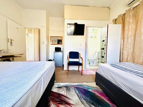 a bedroom with two beds and a chair and a bathroom at Executive Accommodation Bellville 1 in Bellville