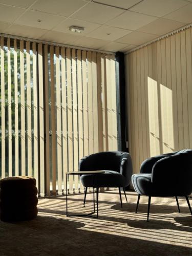 three chairs and a table in a room with large windows at Sure Hotel by Best Western Les Portes de Montauban in Montauban