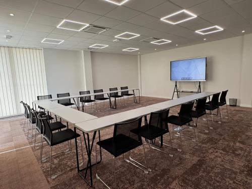 a conference room with a table and chairs and a screen at Sure Hotel by Best Western Les Portes de Montauban in Montauban