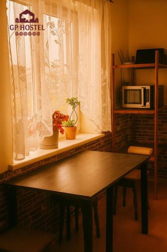 a table in front of a window with a microwave at GP Hostel in Šiauliai