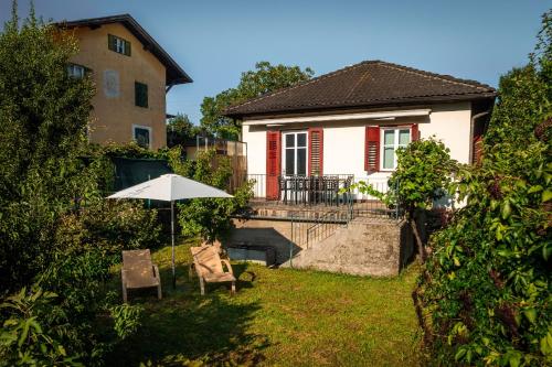a house with an umbrella and chairs in the yard at Villetta Allegra in Appiano sulla Strada del Vino