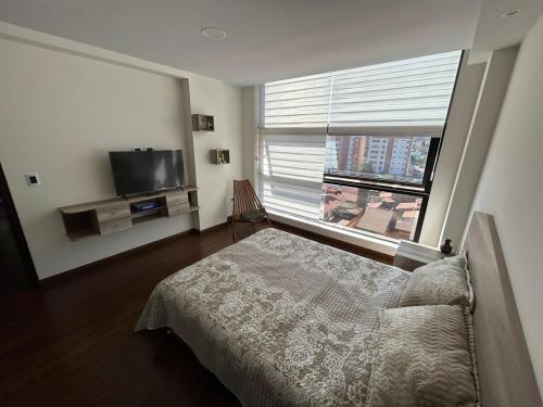 a bedroom with a bed and a large window at Amplio, Familiar y Acogedor in Cochabamba