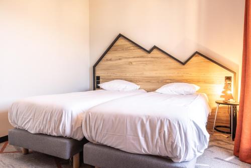 a bedroom with a large bed with a wooden headboard at Hotel Base Camp Lodge - Albertville in Albertville