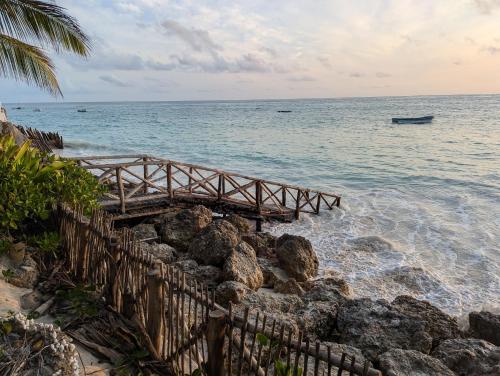 a wooden bridge over the water on a beach at Villa Juliana in Jambiani