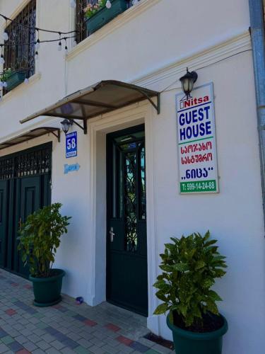 a guest house with a sign in front of a door at Nitsa Guest House in Gori
