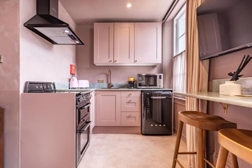 a kitchen with white cabinets and a white refrigerator at The Rokxy Townhouse & Residences - Kings Cross in London