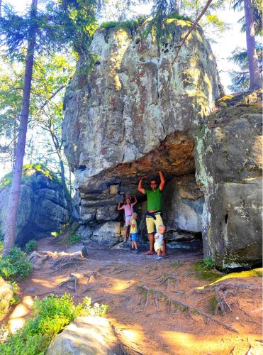 a man and two children standing in front of a rock at Glamping Niebiańska Osada Jurty Dolnośląskie & SPA in Polanica-Zdrój