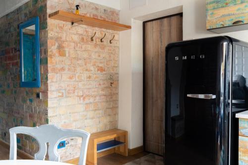 una cucina con muro di mattoni e frigorifero nero di ATTIC Apartment in Old Town Heart Kurpiai a Klaipėda