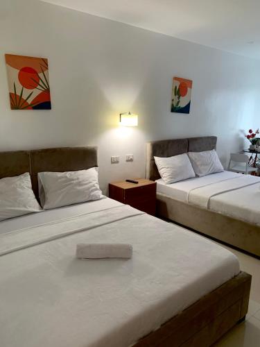 BabakにあるRicres Hometel R3のベッドが2つとランプ付きのテーブルがある部屋
