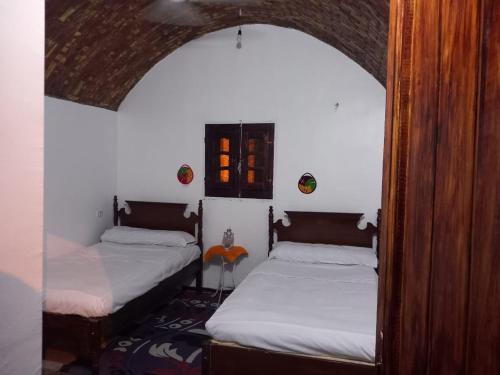 two beds in a room with an archway at Soul House in Jazīrat Fīlah
