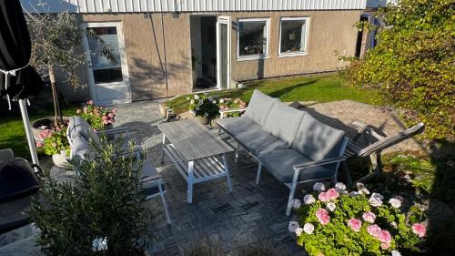 a patio with a couch and a table and flowers at Casa Hönö Hästen in Hönö