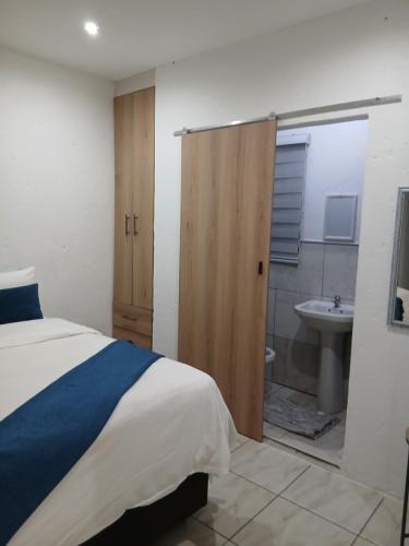 Un dormitorio con una cama y un baño con lavabo. en Russell's Rest Apartments, en Johannesburgo