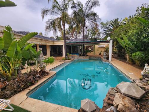 Villa Sant Andrea Boutique Luxury Villa في جوهانسبرغ: مسبح امام بيت فيه نخيل