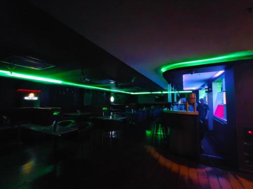 a dark room with a bar with green lights at Holiday Residency Coimbatore in Coimbatore