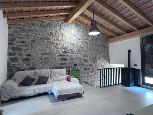 a living room with a couch and a stone wall at Quiet village house in L’ Esquirol