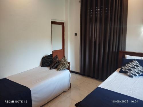 a bedroom with two beds and a mirror at Grand Jumbo residence in Bandarawela