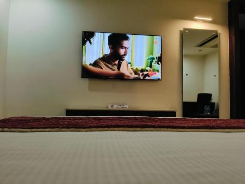 a tv hanging on a wall in a bedroom at Holiday Residency Coimbatore in Coimbatore