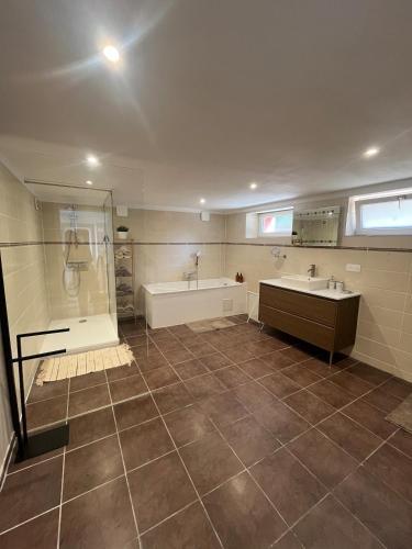 a bathroom with two sinks and a tub and a shower at Maison cosy - salle de jeux, cinéma et jacuzzi in Ittenheim