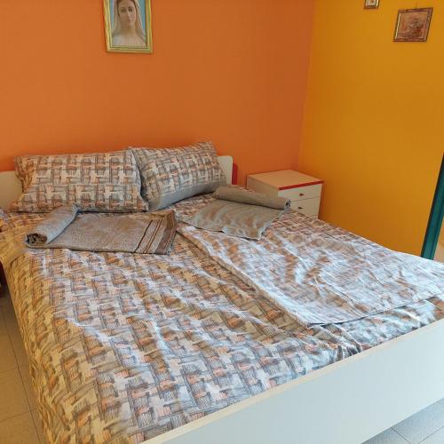 a bed in a bedroom with an orange wall at Casa Zàgará in Schisò