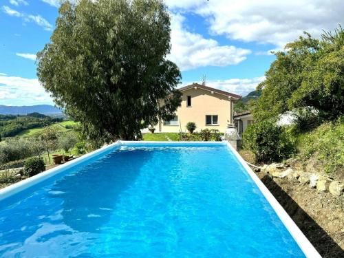 a blue swimming pool in front of a house at Panoramic Villa In The Lucca Hills in Capannori