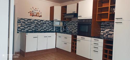 a kitchen with white cabinets and black appliances at Entre Ville & Nature-Sejour idéal a Massy in Massy