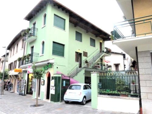 a white car parked in front of a green building at Hotel Alpino in Malcesine