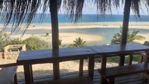 a view of a beach from a porch with a bench at Stunning sea view, charming beach house in Barra, Mozambique - 4x4 in Miramar