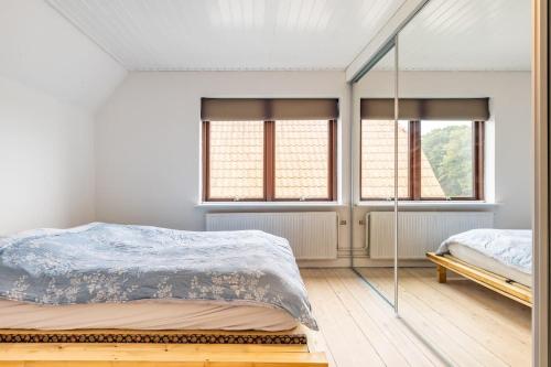 a bedroom with a bed and two windows at MuremesterVilla ved Hav og Skov in Stubbekøbing